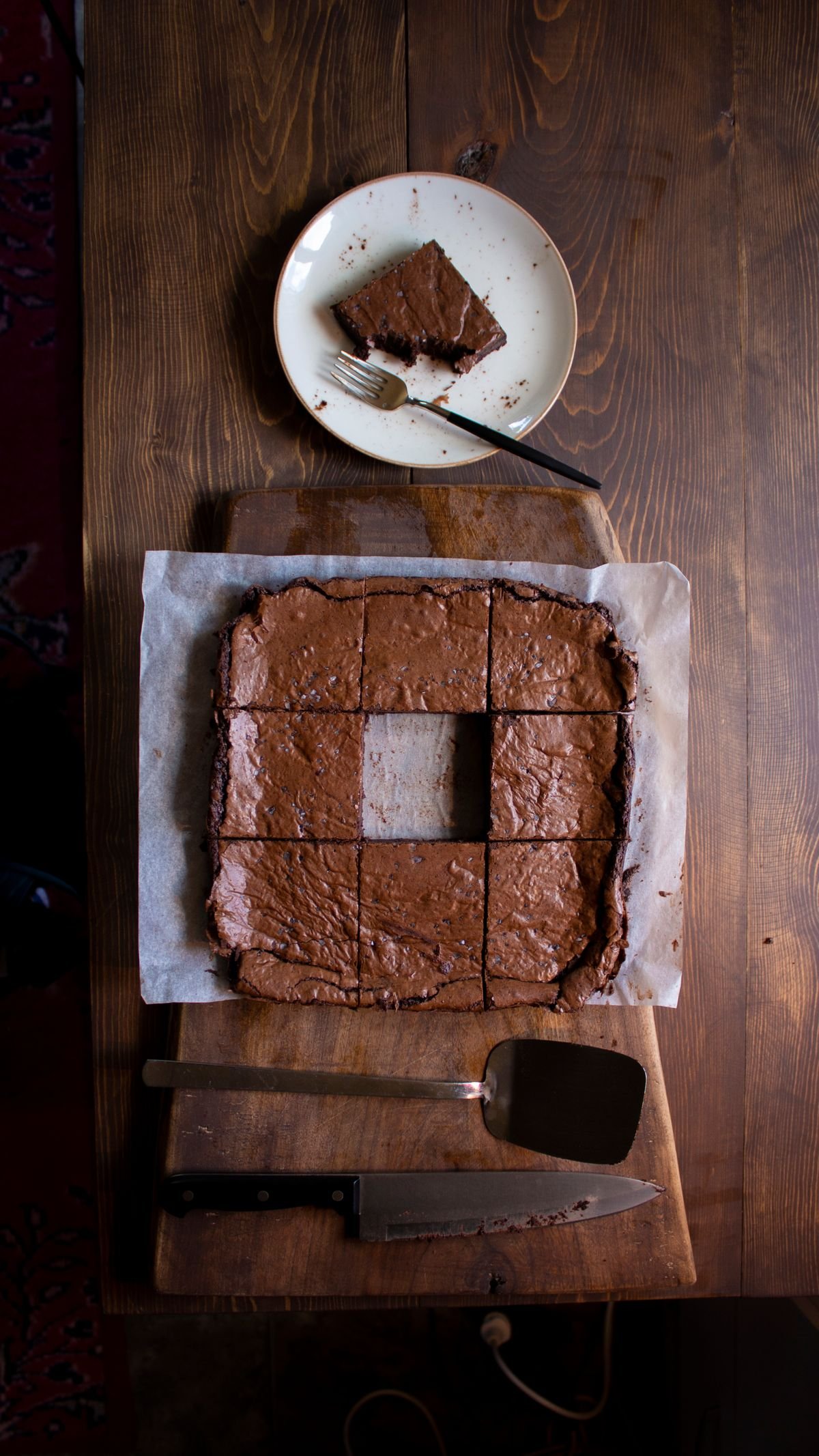 A tray of fudgy brownies cut into squares on parchment