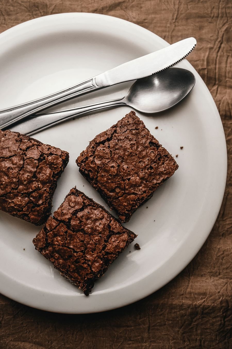 Fudge brownies with shiny, cracked tops on a plate